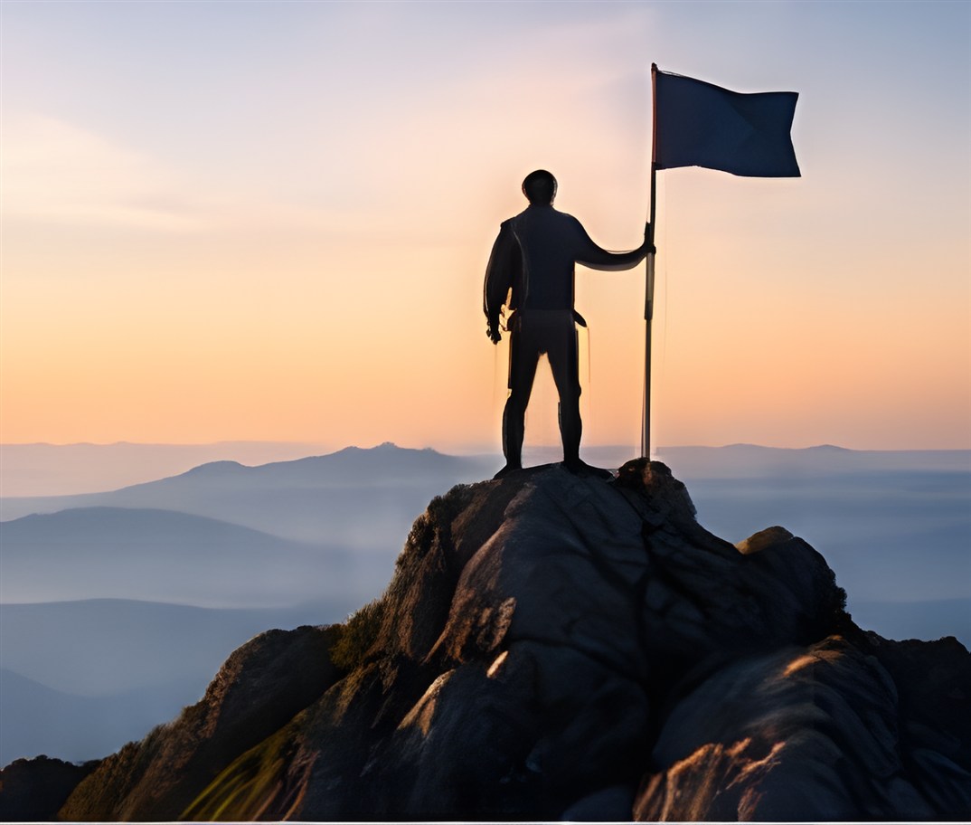 Silhouette of a person holding a flag on a mountain summit at sunrise
